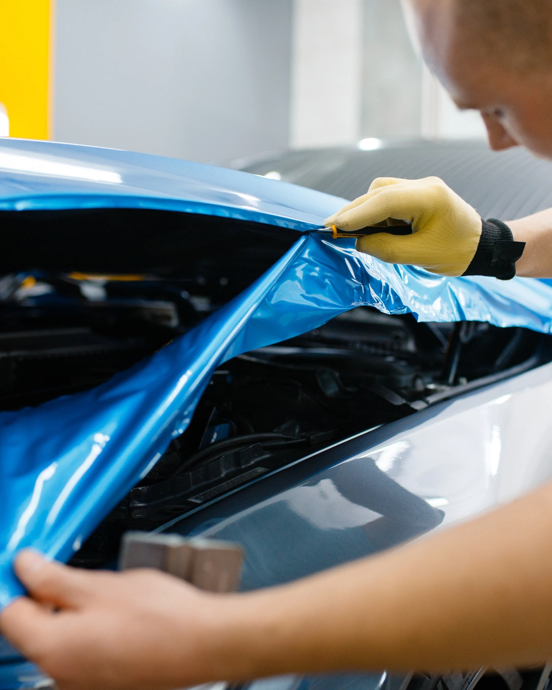 Technician installing colorful graphics wrap on a car